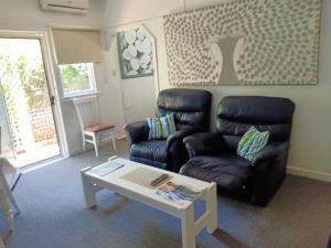 a living room with a black leather chair and a coffee table at The Boathouse a 3 Bedroom House in Narooma