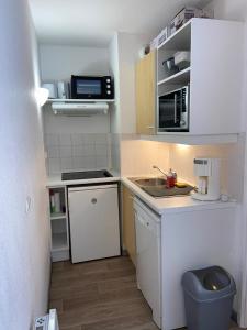 a small kitchen with a sink and a microwave at Appartement lumineux aux pieds des pistes in Saint-François-Longchamp