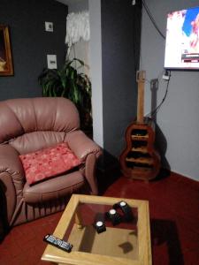 sala de estar con sofá de cuero y guitarra en Confort y tranquilidad al 100% en Malargüe
