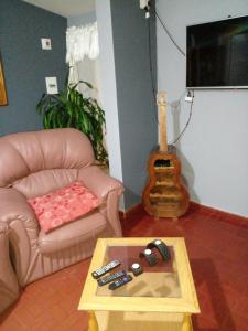 ein Wohnzimmer mit einem Sofa, einem Tisch und einer Gitarre in der Unterkunft Confort y tranquilidad al 100% in Malargüe