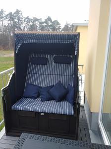 un banc avec des oreillers bleus sur un balcon dans l'établissement Ferienwohnung KWi 17 OG "Küsten-Koje", à Graal-Müritz