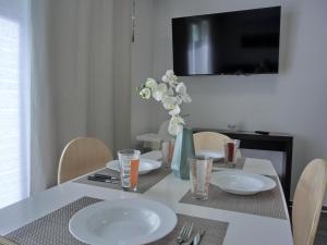 una mesa de comedor con platos blancos y un jarrón de flores en Ferienwohnung KWi 84 EG en Graal-Müritz
