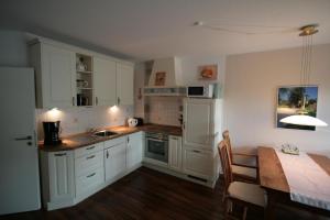 a kitchen with white cabinets and a table and a dining room at Ferienwohnung M30 in Graal-Müritz