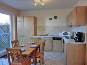 eine Küche mit einem Holztisch und Stühlen sowie eine Küche mit einer Spüle in der Unterkunft Ferienwohnung E1 in Graal-Müritz