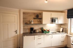 a kitchen with white cabinets and a bowl of fruit on the counter at Apartment Isermann 1 in Westerland (Sylt)