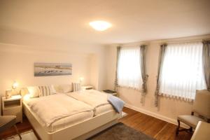 a bedroom with a white bed and two windows at Apartment Isermann 1 in Westerland (Sylt)
