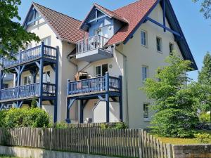 een huis met blauwe balkons en een hek bij Ferienwohnung M31 "Die Welle" in Graal-Müritz