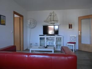a living room with a red couch and a tv at Ferienwohnung P20 "Badenixe" in Graal-Müritz +3 photos