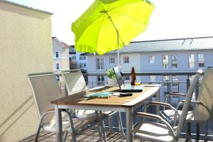 einen Tisch und Stühle mit gelbem Regenschirm auf dem Balkon in der Unterkunft Ferienwohnung L47 in Graal-Müritz