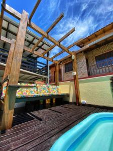 a wooden deck with a pergola and a swimming pool at Pousada Gruta do Monge in Bombinhas