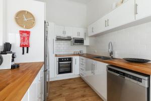 a kitchen with white cabinets and a clock on the wall at Lazy Days 1 in Noosaville