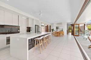 an open kitchen with white cabinets and bar stools at Bird of Paradise Holiday Home with Heated Pool in Palm Cove