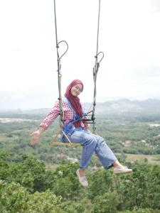 a woman is swinging on a rope swing at Gunung Dago Resort Bogor Syariah in Bogor