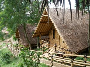 mały dom z dachem krytym strzechą i płotem w obiekcie Gunung Dago Resort Bogor Syariah w mieście Bogor