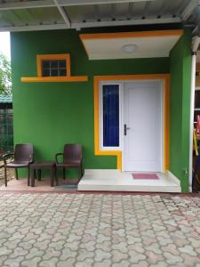 a green wall with two chairs and a white door at Bu Sur Homestay in Bogor