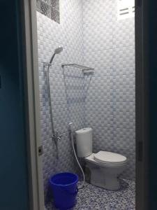 a bathroom with a toilet and a blue bucket at Bu Sur Homestay in Bogor