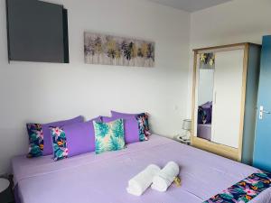 ein Schlafzimmer mit einem lila Bett mit zwei Handtüchern darauf in der Unterkunft Lokai house in Bora Bora