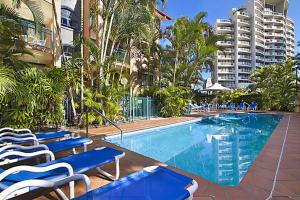 a swimming pool with blue lounge chairs and buildings at Aruba Surf Resort in Gold Coast