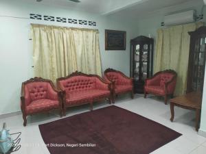 a living room with red couches and a table at Teratak Port Dickson Homestay Mus Only in Port Dickson