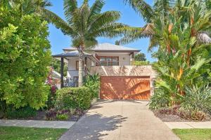 a house with palm trees in front of a driveway at Bird of Paradise Holiday Home with Heated Pool in Palm Cove