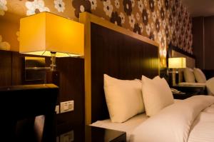 a hotel room with a bed with a headboard and a lamp at Wogo Hotel in Yilan City