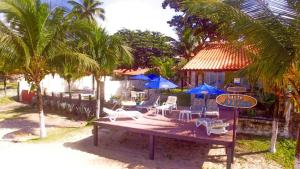 a table with chairs and umbrellas on a beach at Pousada Santo Aleixo in Porto De Galinhas