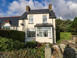 a white house with a garden in front of it at Ty'r Ysgol in Morfa Bychan