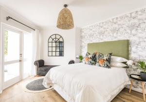 Un dormitorio con una gran cama blanca y una ventana en Plett Holiday Stay with Pizza Oven and Views, en Plettenberg Bay