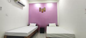 two beds in a room with a purple wall at KRAZYROOMS, Kaziranga in Kāziranga