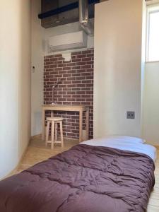 - une chambre avec un lit et un mur en briques dans l'établissement Guesthouse & Lounge FARO, à Iwaki
