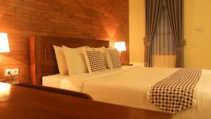 a bedroom with a large bed with white sheets and pillows at Anang Bed & Breakfast Syariah by Ndalem Beong in Magelang