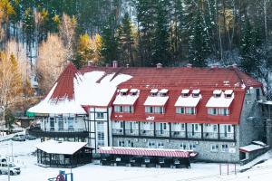ein großes Gebäude mit rotem Dach im Schnee in der Unterkunft Blagodat Resort in Belokuricha