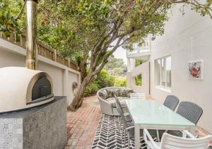 a patio with a table and a fireplace at Plett Holiday Stay with Pizza Oven and Views in Plettenberg Bay