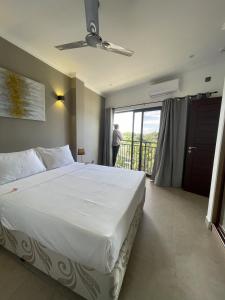 ein Schlafzimmer mit einem großen weißen Bett und einem Balkon in der Unterkunft B Holiday Apartments in Beau Vallon
