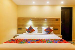 a bedroom with a large white bed with colorful pillows at FabHotel Surya Grand I in Vijayawāda