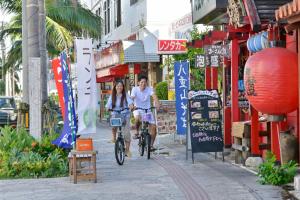 a boy and a girl riding bikes down a street at Ishigakijima Hotel Cucule in Ishigaki Island