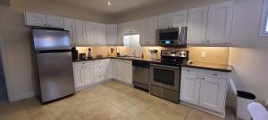 cocina con armarios blancos y nevera de acero inoxidable en 2 bdrm, kitchen, laundry, weeklymonthly discount, en Richmond Hill