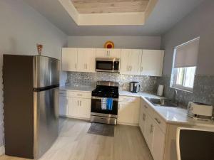 a kitchen with a stainless steel refrigerator and white cabinets at Nicoles Nest Brand New Exquisite Studio Hideaway in Freeport