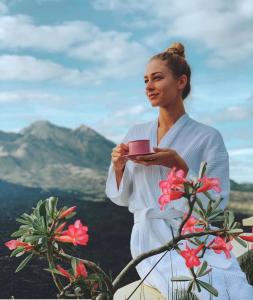 a woman in a white dress holding a pink object at Ayodya Batur Villa in Kintamani