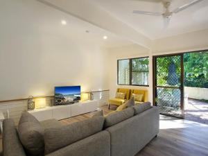 a living room with a couch and a tv at Little Cove Townhouse 2 Pandanus Street 14 in Noosa Heads