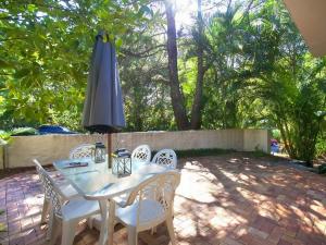 a table and chairs with an umbrella on a patio at Little Cove Townhouse 2 Pandanus Street 14 in Noosa Heads