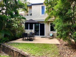 a patio with a table and chairs and an umbrella at Little Cove Townhouse 9 Pandanus Street 14 in Noosa Heads