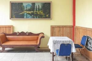 a couch in a room with a table and a painting at Bromo 22 Homestay Syariah near Terminal Bayuangga Probolinggo Mitra RedDoorz in Pilang