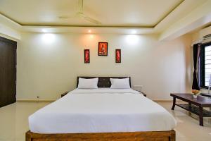 a bedroom with a large white bed and a table at FabHotel White House - Nr Sinhagad speciality Hospital in Pune