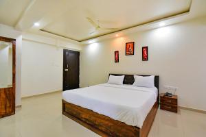 a bedroom with a large bed with white sheets at FabHotel White House - Nr Sinhagad speciality Hospital in Pune