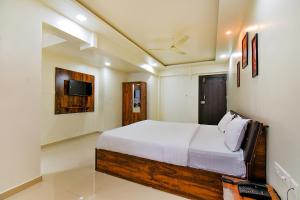 a bedroom with a bed and a tv on the wall at FabHotel White House in Pune