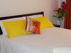 a bed with yellow and orange pillows on it at Baraka Home in Nairobi