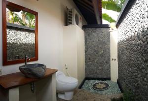 un bagno con lavandino, water e finestra di Mango Tree Inn a Pemuteran