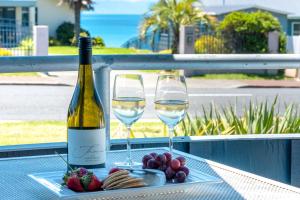 a bottle of wine and two glasses on a table at Oneroa Bay Villas in Oneroa
