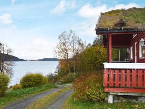 a red house on a hill next to the water at 6 person holiday home in VATNE in Vatne